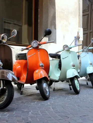 Classic italian scooters parked in ancient street old town at Treviglio Vintage festival. Piaggio Vespa Italy vintage scooters.