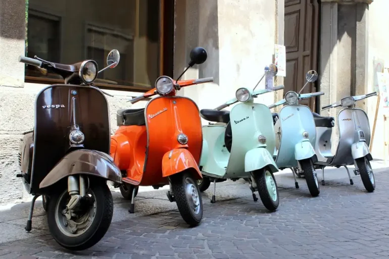 Classic italian scooters parked in ancient street old town at Treviglio Vintage festival. Piaggio Vespa Italy vintage scooters.