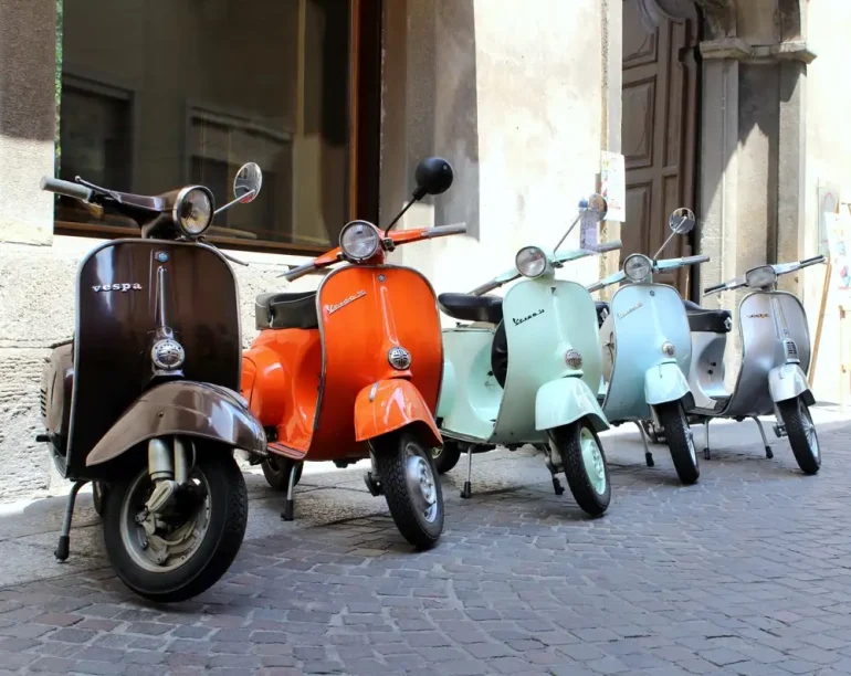 Classic italian scooters parked in ancient street old town at Treviglio Vintage festival. Piaggio Vespa Italy vintage scooters.